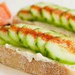 Crostini with cucumber slices, cream cheese and a sprinkle of red chile powder