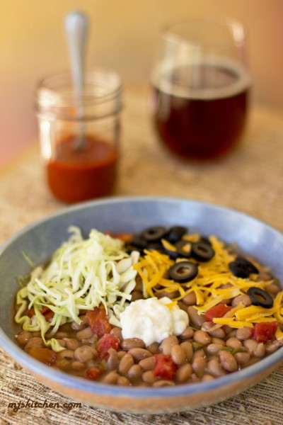 A bowl of pinto beans with an assortment of toppings